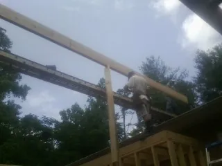Carpenter setting a ridge beam over a new addition frame in Drexel