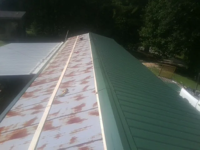 Old rusted panels beside newly installed green metal roofing — Wind Damage Roof Repair by Roofing Brothers in Drexel