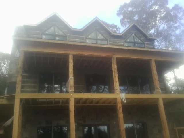 Dormers and porch framing on a large log home under construction — Roof Coating work by our crew in Drexel