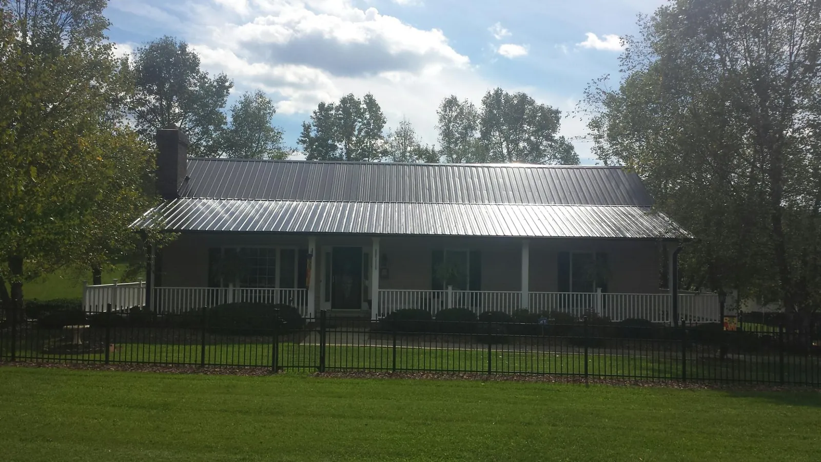 Gray metal roof on a brick ranch with a full width front porch — Gutter Guard Installation work by our crew in Drexel